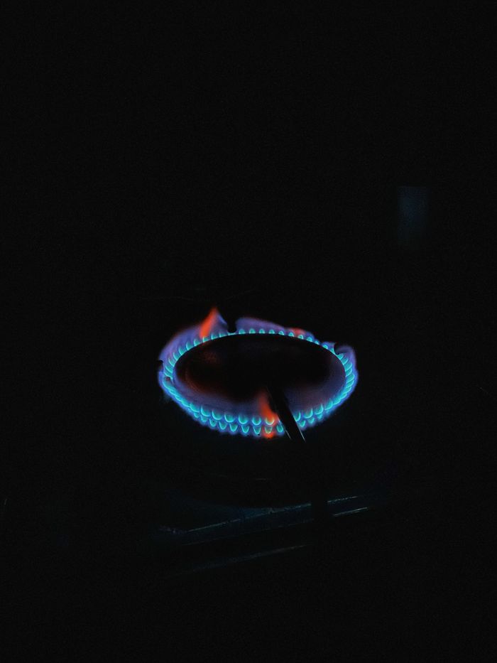 Vibrant blue gas flame on a stove burner, showcasing energy and heat.